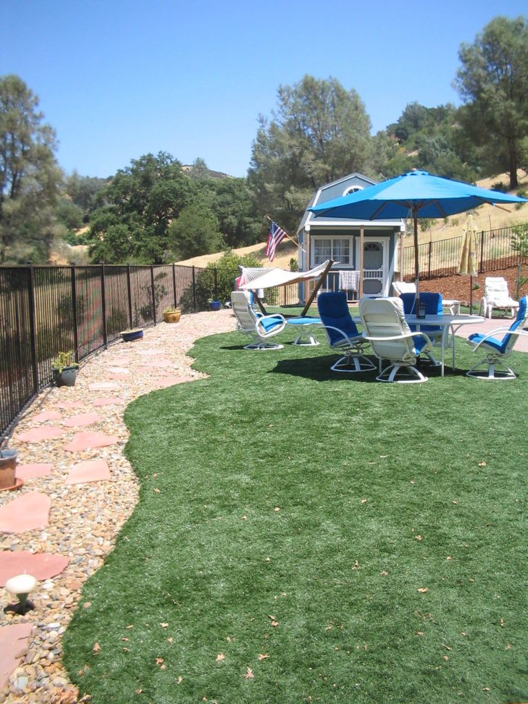 Set on a sunny slope deep in the Sierra Nevada foothills, this artificial grass lawn play yard is the outdoor destination of this active family! Featuring our unique rolled edge, we designed the edge to help shed rain fall and snow melt into drainage hidden under the rock and flagstone; weeping out beyond the fence and down slope.