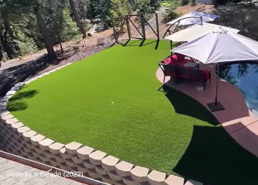 A photo of a stunning transformation from bark and dirt to this lush ever green artificial grass lawn just off the deck of a pool in the Sierra Foothills.